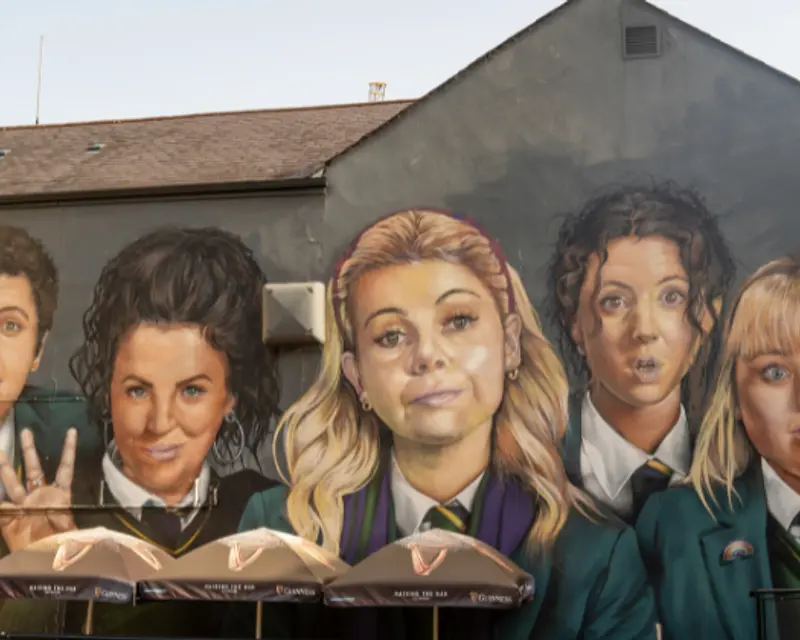 side of a building with the characters of Derry girls painted on the side