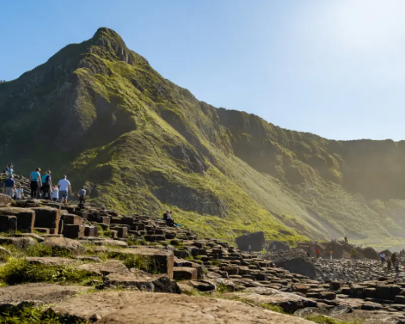 rocky stone of the Giants Causeway with a green mountain in the background