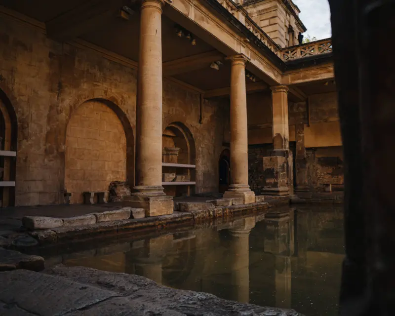 Ancient Roman baths with columns and water, showcasing historic architecture and serene surroundings. Ideal for small group tours.