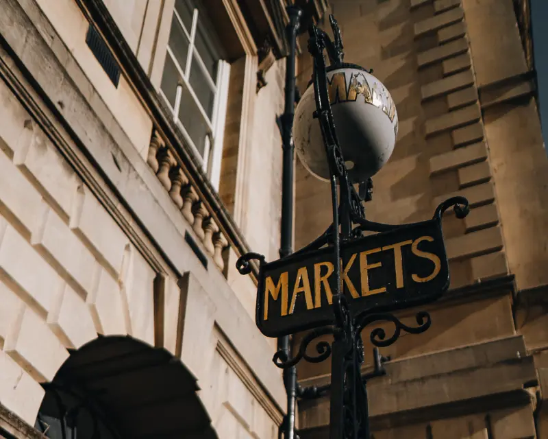 Vintage street sign reading "MARKETS" against a historic building, capturing the charm of UK towns and local attractions.