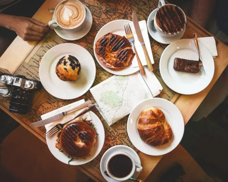 A table spread with coffee, pastries, and a map, suggesting a cozy break during a small group tour in the UK.