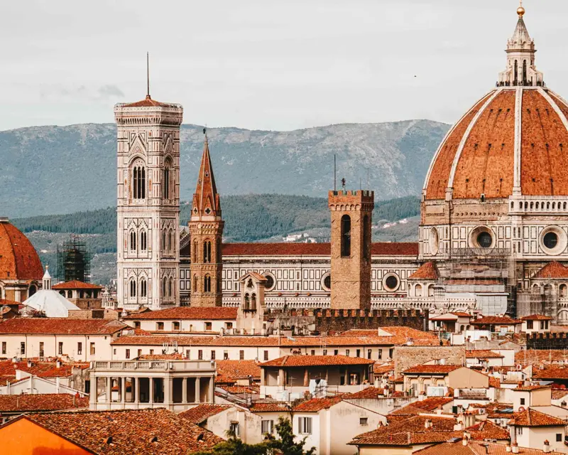 Scenic view of Florence, Italy, showcasing the Duomo, bell tower, and rooftops surrounded by rolling hills.