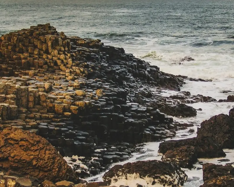 Breathtaking view of the Giant's Causeway, featuring unique hexagonal rock formations against a backdrop of crashing waves.