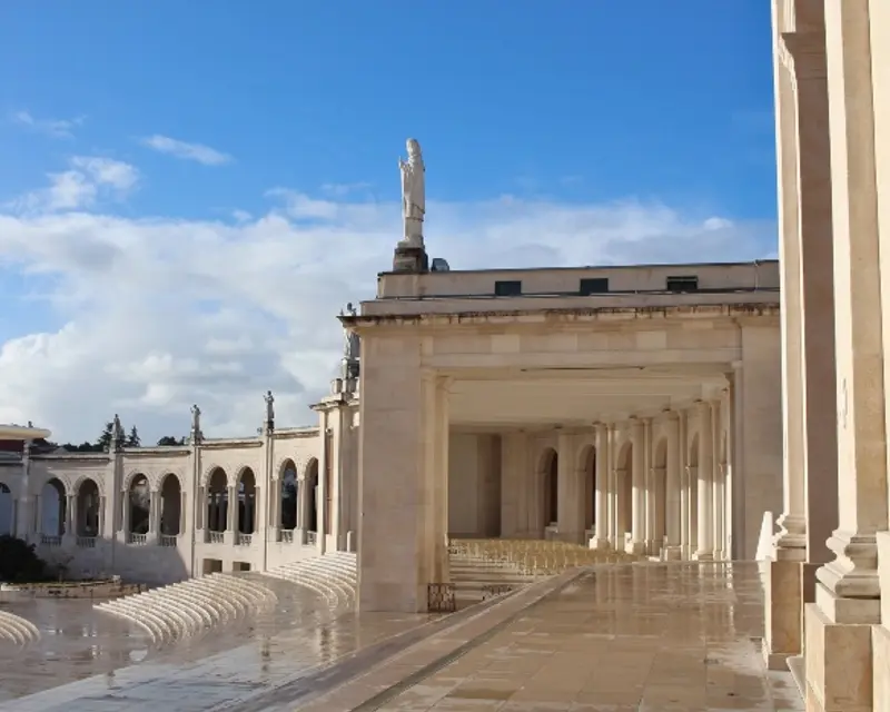 A serene architectural view showcasing classic columns and a statue, under a partly cloudy sky. Perfect for tours.