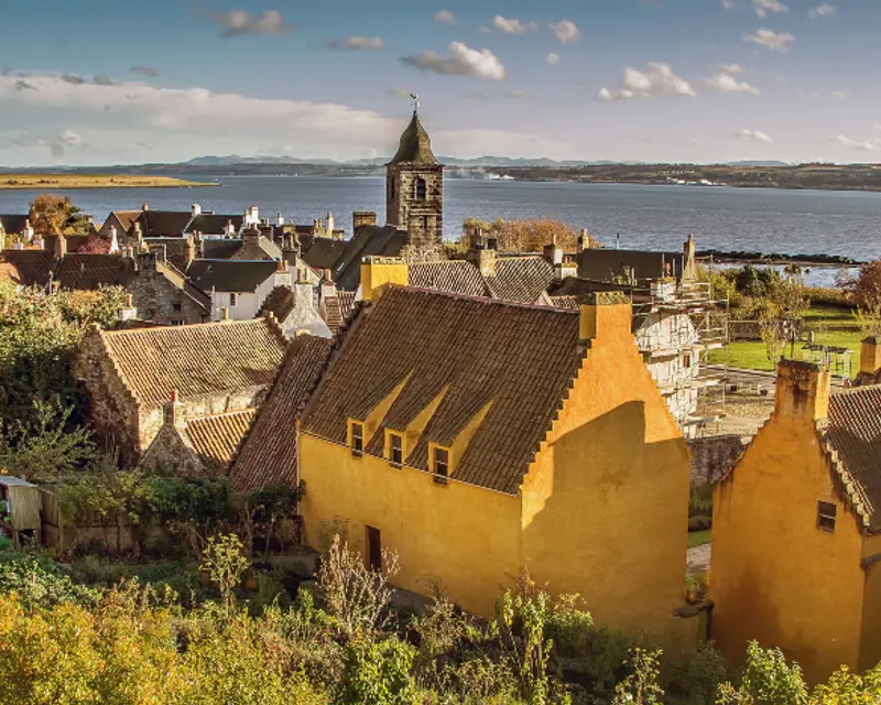 Charming seaside village with colorful houses, a historic clock tower, and scenic views of the water and surrounding landscape.