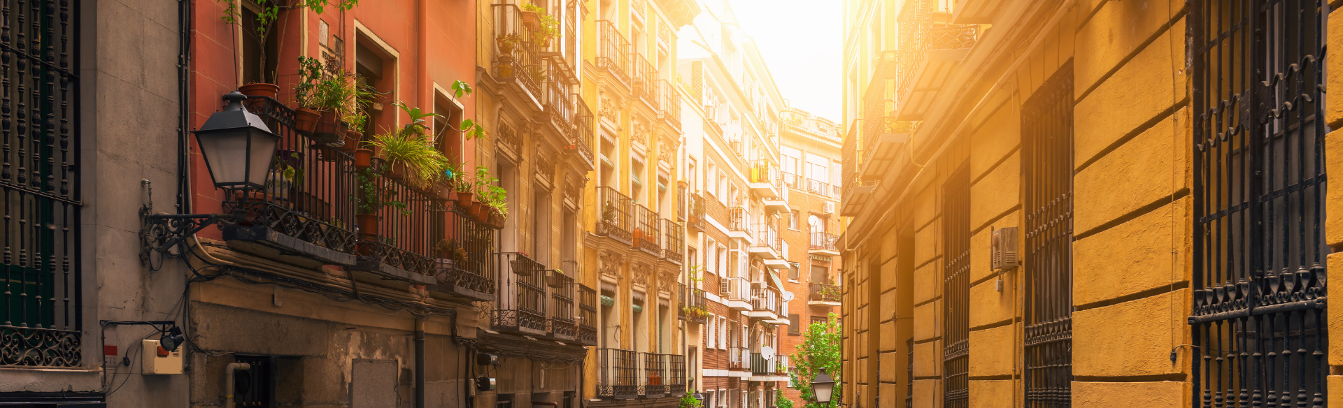 tall buildings in different shades of orange line either side of a narrow street in Spain