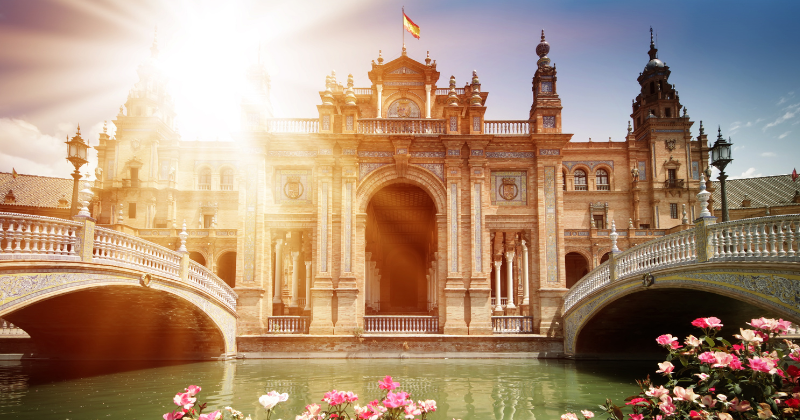 Sunlight glints from behind the majestic Seville Palace which can be seen following direct flights to Spain from USA