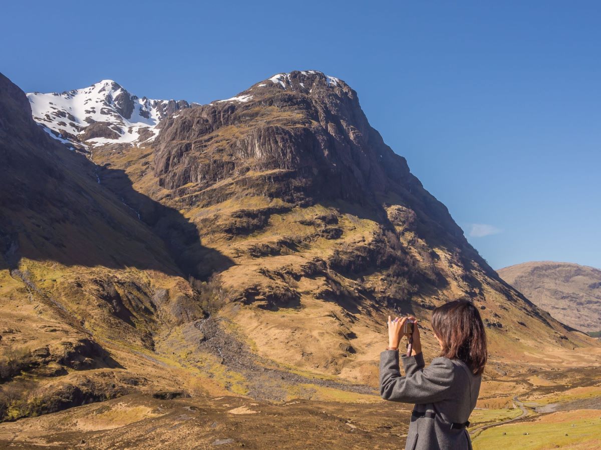 Women taking a photograph of the landscape with a mountain in the background