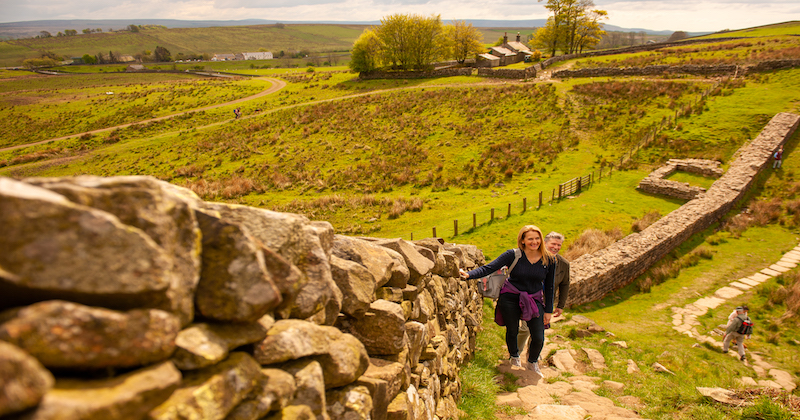 two walkers hiking up a field in the english countryside