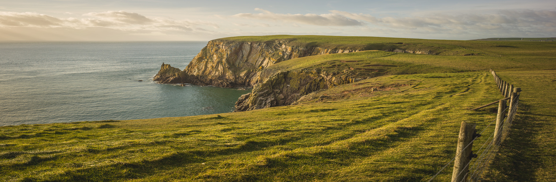 A stunning view of green cliffs over the coast which can be seen on a visit Dumfries and Galloway.