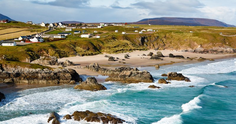 Turquoise water lapping at the golden sand of Durness beach which can be visited via flights to Scotland from USA