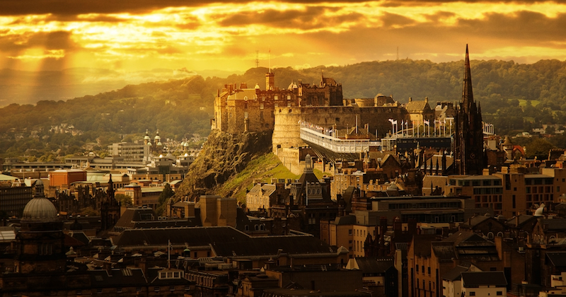 A view across Edinburgh city to Edinburgh castle under a stormy orange sky