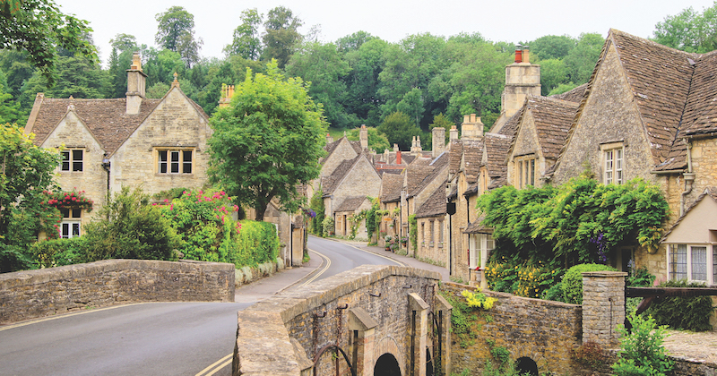 a picturesque village in England with pretty cottages surrounded by green trees