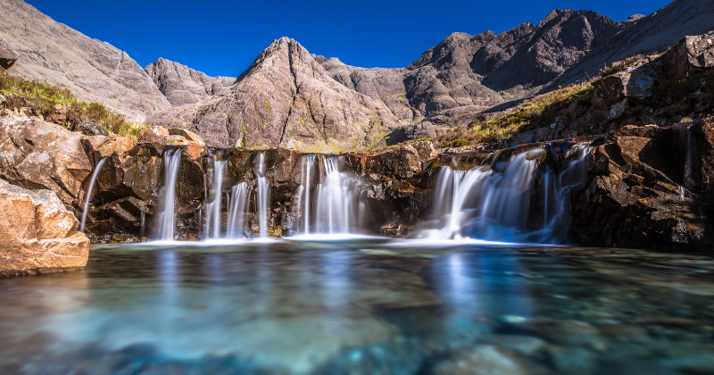 the mesmerisingly beautiful azure blue water of the fairy pools in Skye is one of the best things to see in Scotland