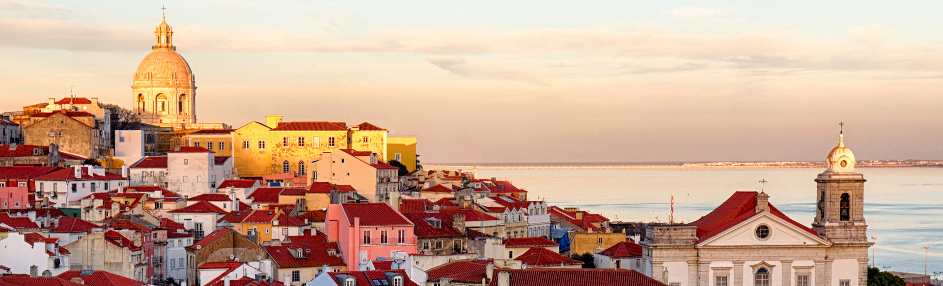 The colorful skyline of a Portuguese city at sunset with the sea in the distance