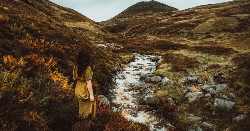 solo traveller next to a stream looking at the view