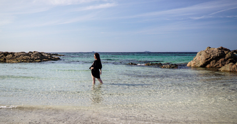 solo traveller standing in the sea at Iona beach