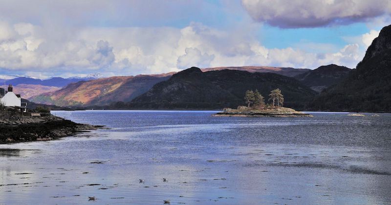 a view of an island in the middle of loch carron surrounded by Scottish hills