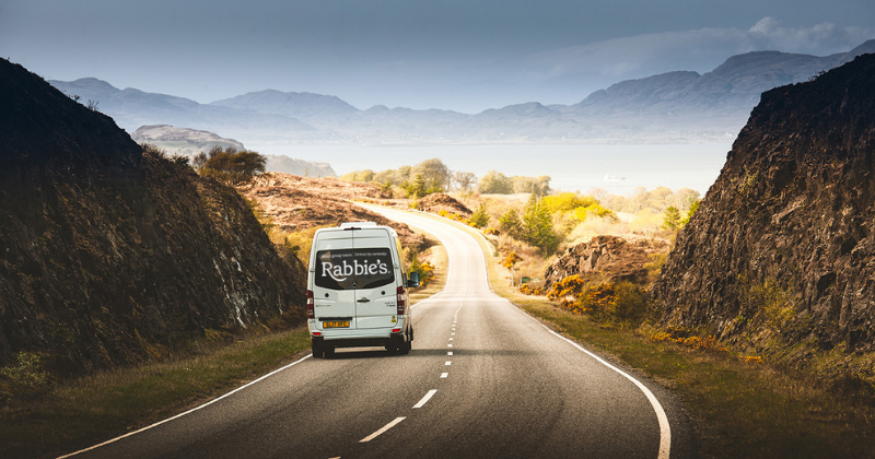 a rabbies luxury tour bus driving off to explore Scotland from Edinburgh