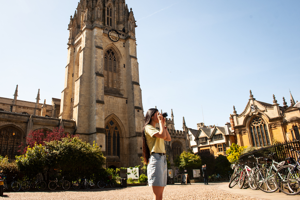women with a camera taking a photo of Oxford's buildings