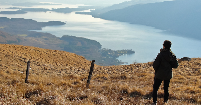 a man admiring an astonishing view of Loch Lomond from the Scottish hills
