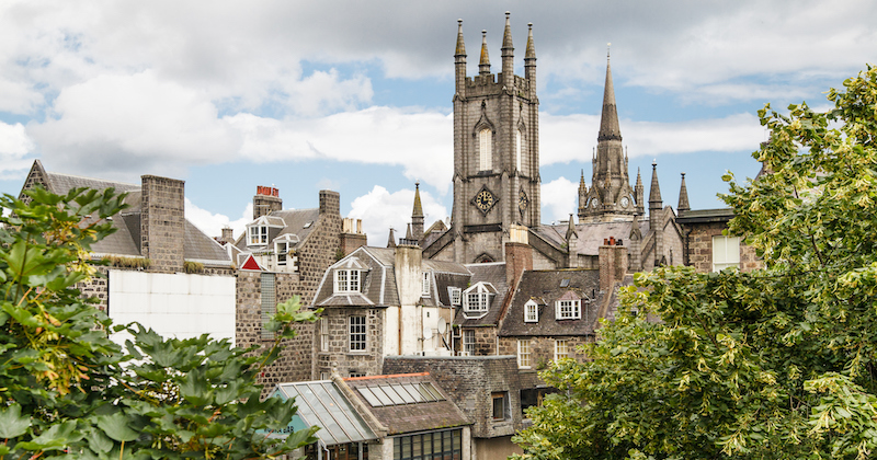 the iconic city skyline of Aberdeen with green trees under a blue sky filled with fluffy white clouds