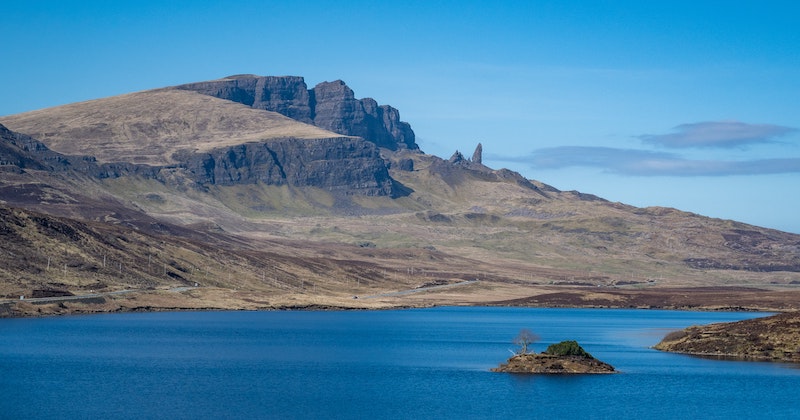 the rugged hillside with the Old Man Of Storr jutting steeply up under a blue sky
