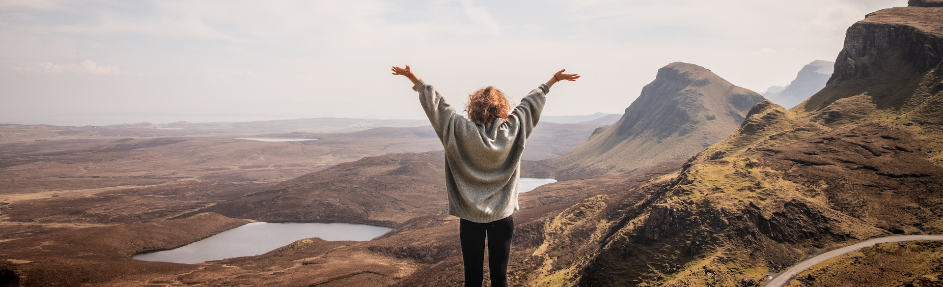 A solo traveller embracing the adventure standing overlooking mountains and lakes