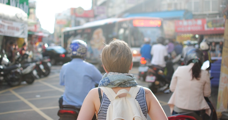 female solo traveller in busy street surrounded by people and bikes