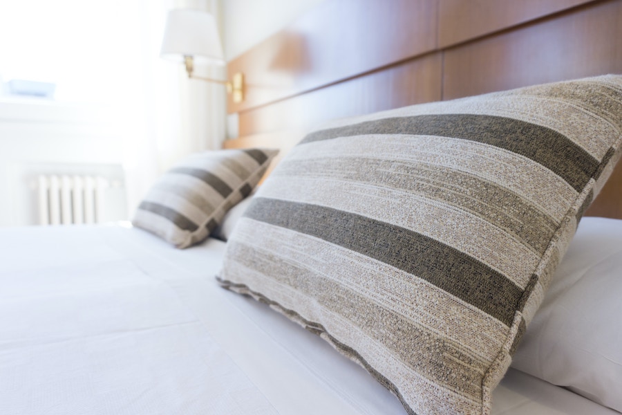 hotel bed with two striped pillows on a white duvet set 