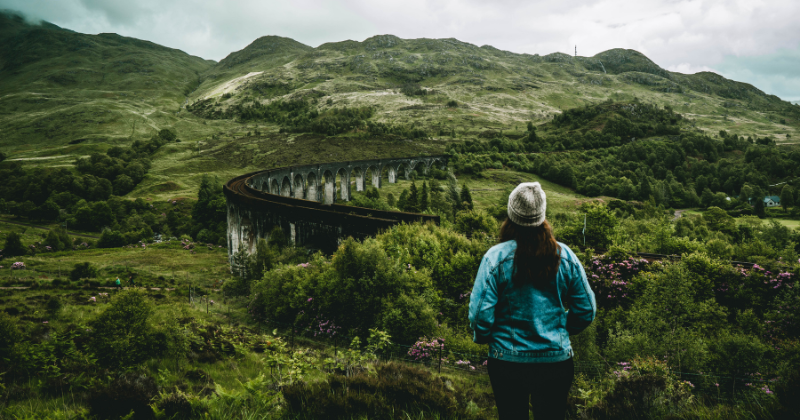 solo traveller looking out over the Glenfinnan Viaduct Scotland