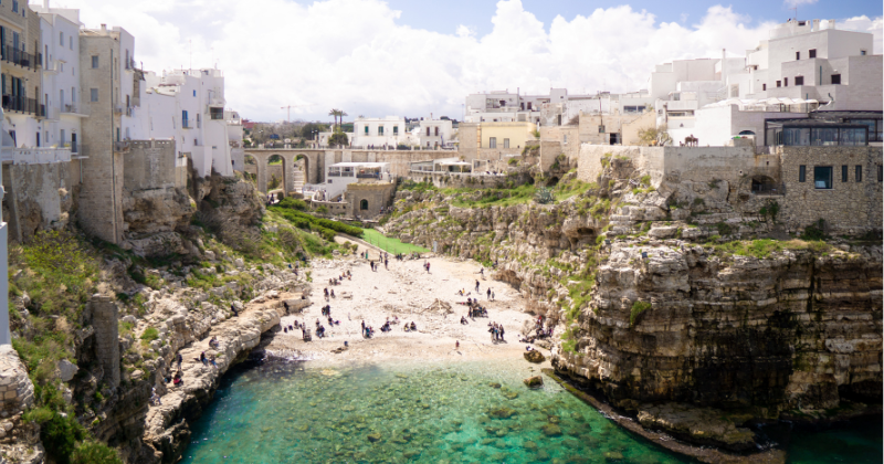 a beautiful cove with clear water surrounded by a small town in Italy one of the top solo travel destinations