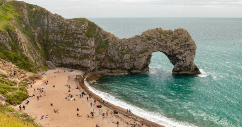 Durdle Door arch stone formation from the cliff edge into the sea