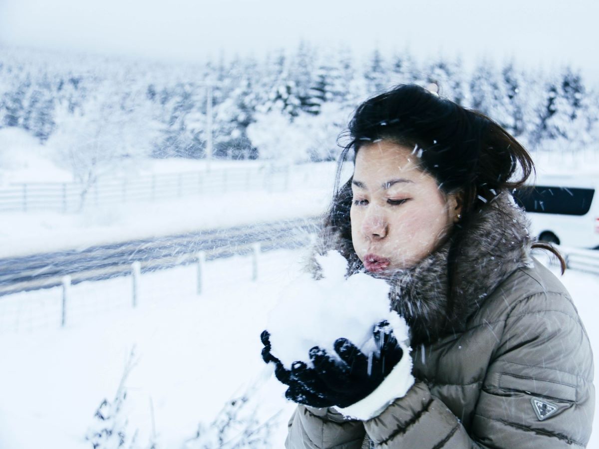 Women blowing a large handful of snow