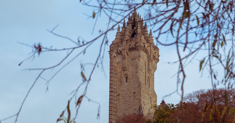 the sandpaper tower of the Wallace Monument breaks through from behind the trees